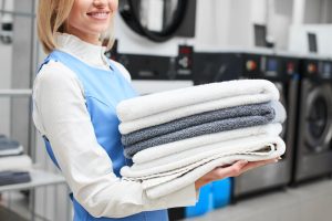 Worker,Laundry,Girl,Holding,Fresh,Towels,In,Her,Hands,And