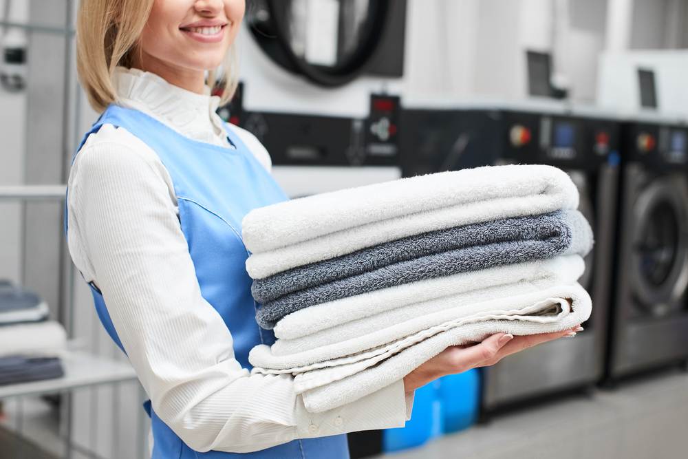 Worker,Laundry,Girl,Holding,Fresh,Towels,In,Her,Hands,And